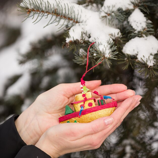 Foto nahaufnahme der hände eines mädchens, das ein hausgemachtes hält. das spielzeug des neuen jahres, das am weihnachtsbaum hängt