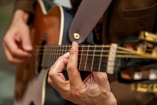 Nahaufnahme der Hände eines Musikers, der Gitarre spielt. Die Finger des Musikers drücken die Saiten der Gitarre. Musiker spielt Bassgitarre