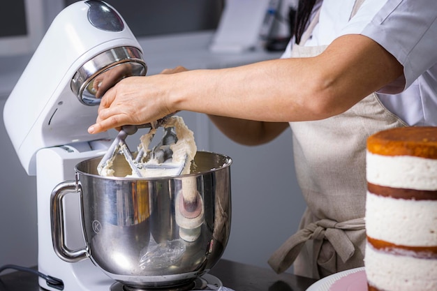 Nahaufnahme der Hände eines professionellen Küchenchefs, der den Teig mit einer Küchenmaschine bearbeitet