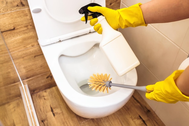 Foto nahaufnahme der hände mit bürste und reinigungslösung zur desinfektion von toilettenflaschenmodellen