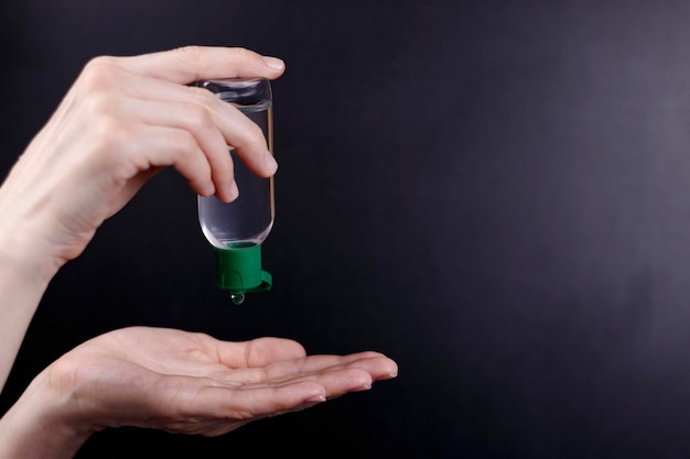 Foto nahaufnahme der hände mit einem antiseptischen gel in einer flasche auf schwarzem hintergrund virenschutz