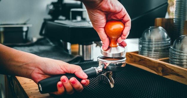 Nahaufnahme der Hand Barista Café Kaffeezubereitung mit manuellen Pressen gemahlener Kaffee mit einem Tamper