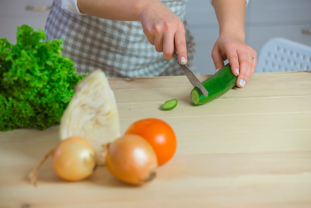 Nahaufnahme der Hand der Frau, die Gemüse mit Messer in der Küche hackt