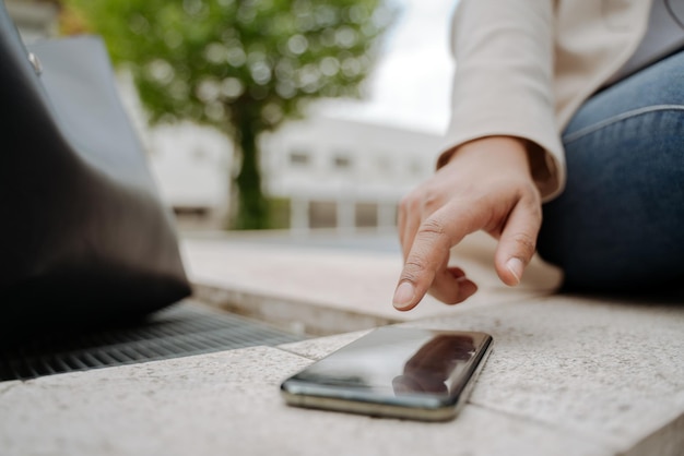 Nahaufnahme der Hand der Geschäftsfrau mit dem Touchscreen des Mobiltelefons, der im Freien arbeitet, selektiver Fokus