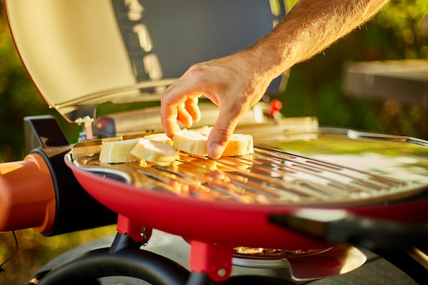 Nahaufnahme der Hand des Mannes, die Bruschetta auf den Grillgasgrill röstet