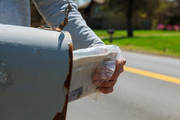 Nahaufnahme der Hand des Mannes, die einen Brief aus dem Postfach außerhalb des Hauses nimmt