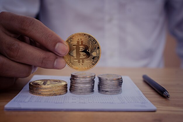 Nahaufnahme der Hand, die Bitcoins hält, um digitale Geldinvestitionen zu finanzieren?