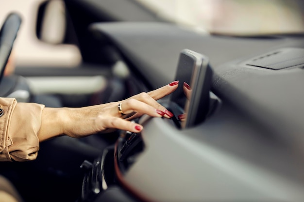 Nahaufnahme der Hand einer Frau, die das GPS in ihrem Auto anpasst