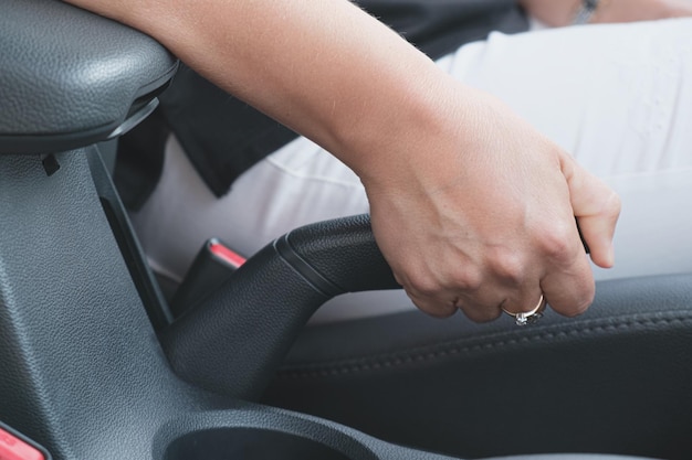 Nahaufnahme der Hand einer Frau, die den Handbremshebel im Auto zieht