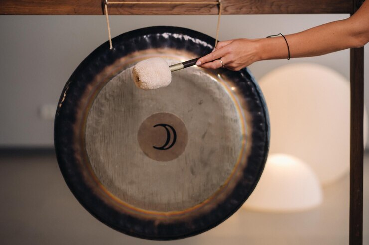 Foto nahaufnahme der hand einer frau, die einen gong mit einem hammer hämmert gong und handschläger für gong