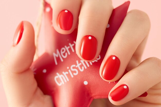 Nahaufnahme der Hand einer Frau mit rotem, minimalistischem Nageldesign. Maniküre, Pediküre-Schönheitssalon-Konzept. Neujahrs-Weihnachtsverkauf