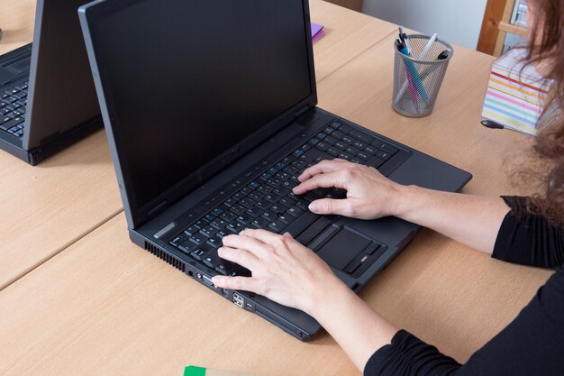 Nahaufnahme der Hand einer Geschäftsfrau, die auf der Laptoptastatur tippt