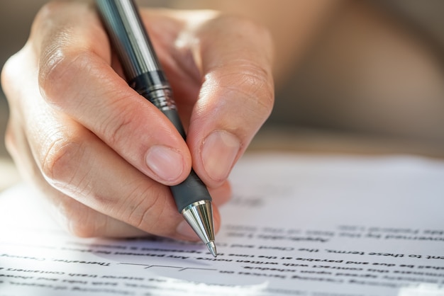 Nahaufnahme der Hand einer Geschäftsfrau, die einen Stift hält, um das Vertragsdokument zu unterzeichnen