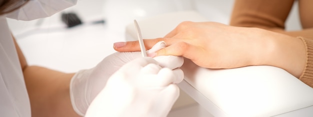 Foto nahaufnahme der hand einer jungen frau, die das nagelfeile-verfahren in einem schönheitssalon erhält