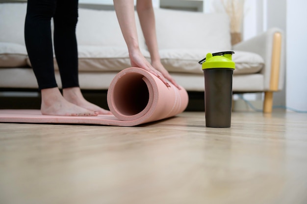 Nahaufnahme der Hand einer jungen Frau, die ein Heimtraining der Fitnessmatte hält