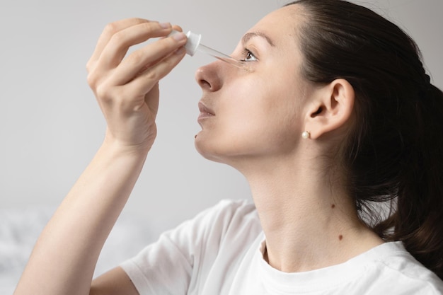 Nahaufnahme der Hand einer weißen Frau, die ätherisches Öl oder Serum für die Haut aufträgt Selbstpflegekonzept