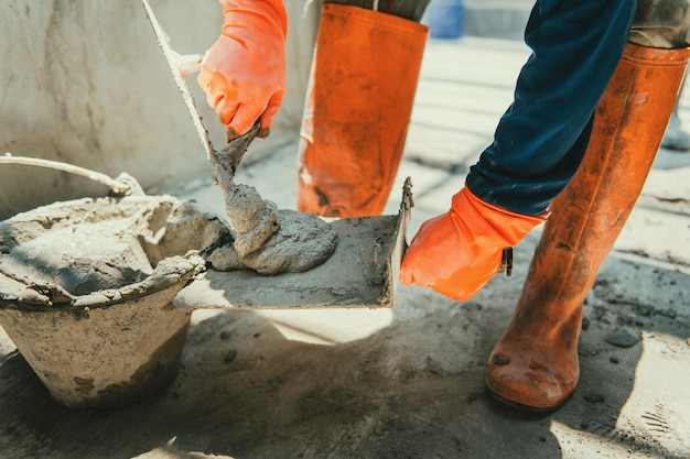 Foto nahaufnahme der hand eines arbeiters, der zement an der wand für den bau eines hauses verputzt