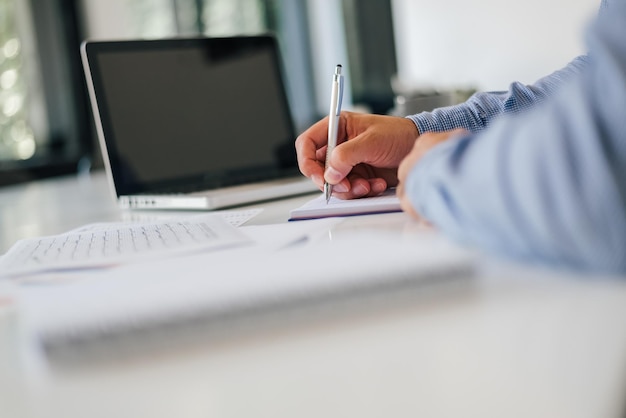 Nahaufnahme der Hand eines Geschäftsmannes, der sich im modernen Büro Notizen macht und Arbeiten oder Arbeitsabläufe plant