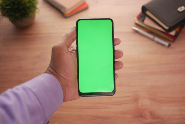 Nahaufnahme der Hand eines jungen Mannes mit Smartphone mit grünem Bildschirm