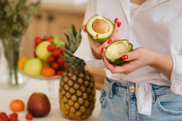 Nahaufnahme der Hand eines Mädchens, die eine Avocado hält, die in zwei Hälften geschnitten wird