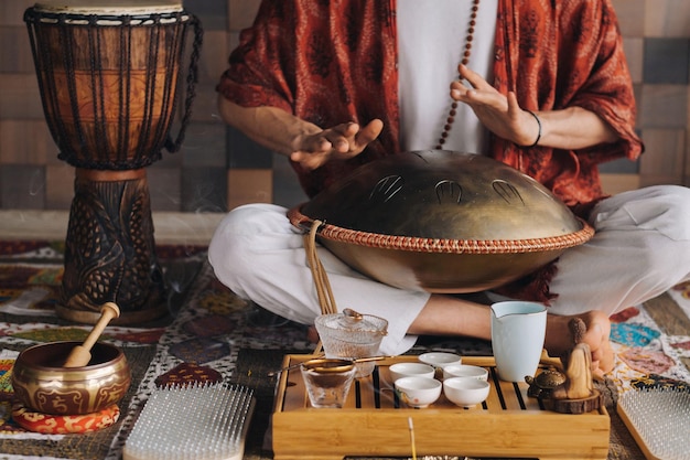 Foto nahaufnahme der hand eines mannes, der während der teezeremonie ein modernes musikinstrument spielt, die orion-zungentrommel