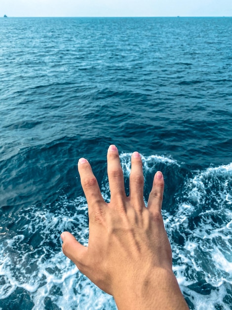 Nahaufnahme der Hand gegen das Meer