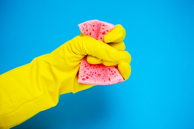 Nahaufnahme der Hand in gelben Handschuhen, die Reinigungsmittel halten