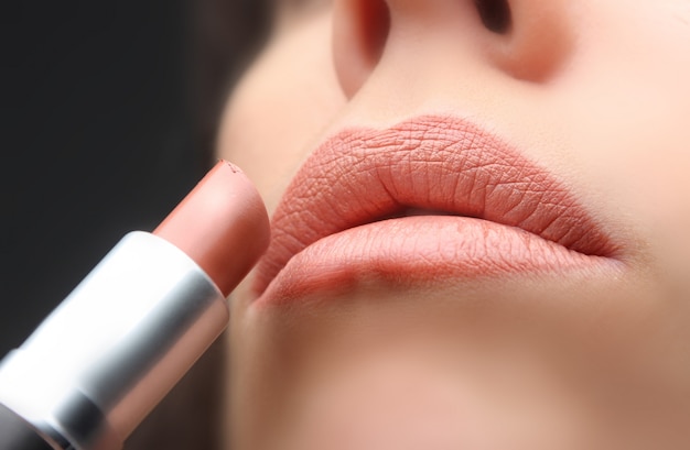 Nahaufnahme der Hand Lippenstift auf Mund setzend