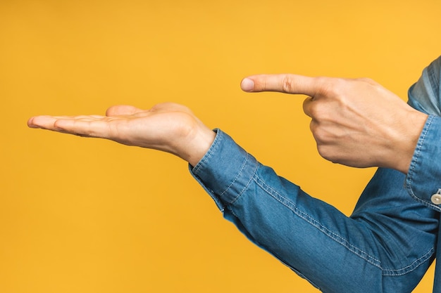 Foto nahaufnahme der hand mit hoding etwas isoliert auf gelbem hintergrund zeigefinger