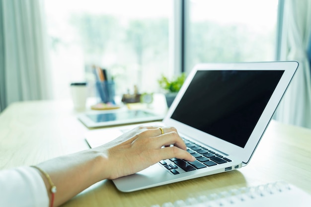 Nahaufnahme der Hand mit Laptop mit schwarzem Bildschirm auf Tisch im Büro. Technologie- und Geschäftskonzept.