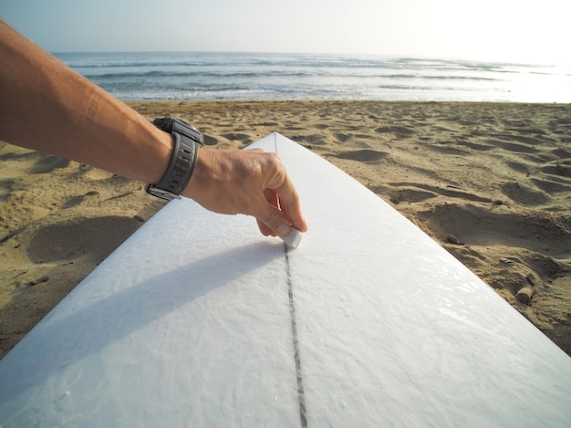 Nahaufnahme der Hand, Wachs auf Surfbrett auftragen, am Strand.