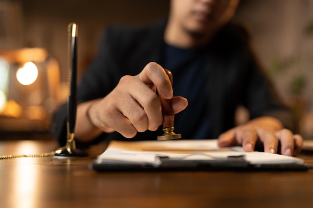 Nahaufnahme der Handstempelung einer Person mit genehmigtem Stempel auf öffentlichem Papier des Zertifikatsdokuments am Notar oder Geschäftsleute arbeiten von zu Hause aus isoliert für den Schutz vor Coronavirus COVID19