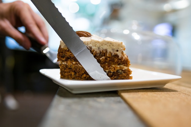 Nahaufnahme der hausgemachten gesunden Karottenkuchenportion, die auf einem Teller im Café serviert wird.