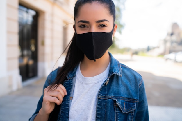 Nahaufnahme der jungen Frau, die Gesichtsmaske trägt, während draußen auf der Straße steht