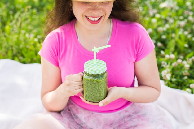 Nahaufnahme der jungen Frau haben Spaß im Park und trinken grüne Smoothies bei einem Picknick.