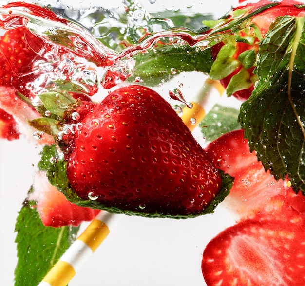 Nahaufnahme der kalten und frischen Limonade mit Erdbeeren, Minzblättern und Eiswürfeln. Textur des kühlenden Sommergetränks mit Makroblasen auf Glas. Zischend oder schwimmend bis zur Oberfläche.