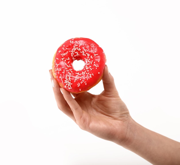 Nahaufnahme der kaukasischen Frauenhand, die einen roten, mit Zuckerglasur glasierten Ringkrapfen hält, isoliert auf weißem Hintergrund, Symbol für ungesundes Ernährungskonzept, niedriger Winkel, Seitenansicht