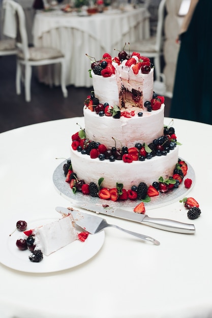 Nahaufnahme der köstlichen süßen Hochzeitstorte verziert mit frischen Erdbeeren, Blaubeeren und Brombeeren. Geschnittene Hochzeitstorte in Nahaufnahme.