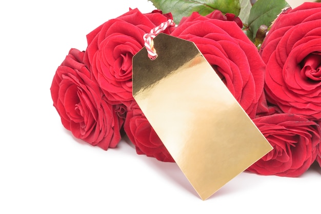 Nahaufnahme der leeren goldenen Marke mit roten Rosen auf weißem Hintergrund. Valentinstag-Konzept