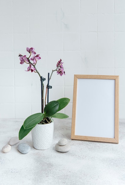 Nahaufnahme der lila Phalaenopsis-Orchidee im Topf und verspotten Sie Plakatrahmen auf dem Tisch