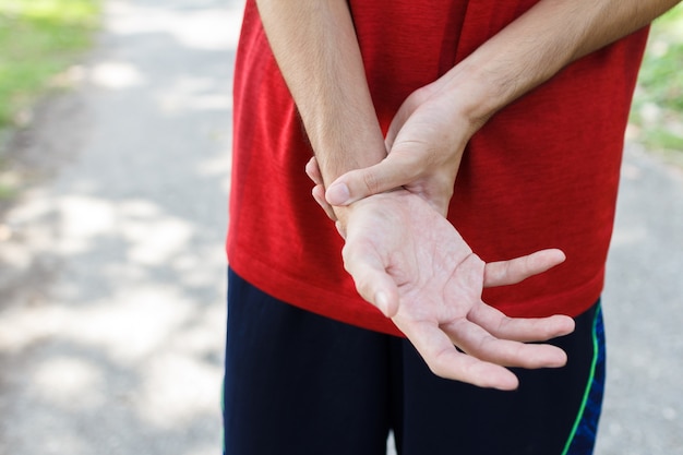 Nahaufnahme der männlichen Arme, die ihr schmerzhaftes Handgelenk wegen Übung halten