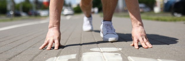 Nahaufnahme der männlichen Person in der Sportuniform, die anfängt, vom niedrigen Start zu laufen