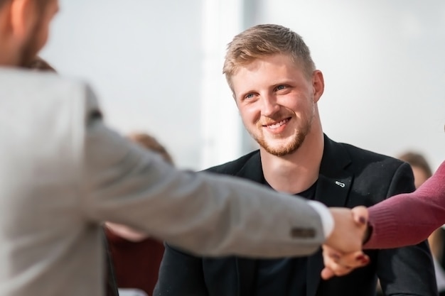 Foto nahaufnahme. der manager und der bewerber geben sich während des vorstellungsgesprächs die hand