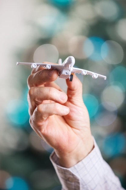 Foto nahaufnahme der mannhand, die modell des flugzeugs auf einem weihnachtshintergrund hält