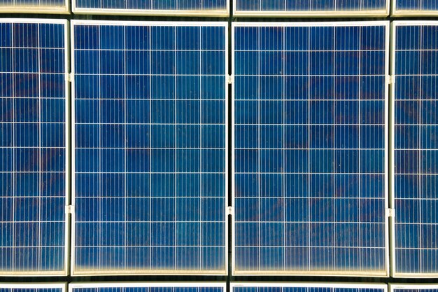 Nahaufnahme der Oberfläche blauer Photovoltaik-Sonnenkollektoren, die auf dem Dach des Gebäudes montiert sind, um sauberen ökologischen Strom zu erzeugen. Produktion eines erneuerbaren Energiekonzepts.