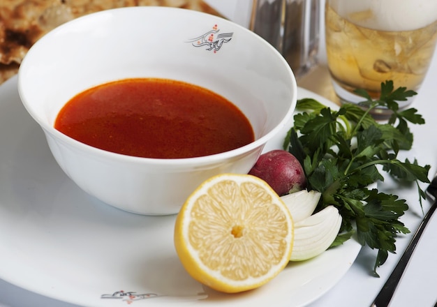 Nahaufnahme der persischen Küche mit Suppe, Gemüse und einer Tasse Saft auf weißem Hintergrund