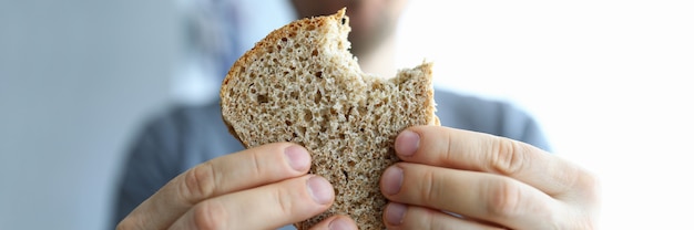 Nahaufnahme der Person, die Scheibe frisches Vollkornbrot hält. Männchen zeigt leckeren Roggen. Bäckerei und handgemacht. Makroaufnahme der Komponente für Sandwich. Diät und Ernährungskonzept