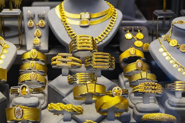 Nahaufnahme der Schmuckgoldhalsketten-Ringarmbänder, die im Schönheitseinzelhandelsgeschäft-Schaufensterhintergrund gezeigt werden