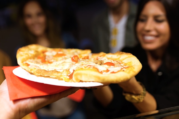 Nahaufnahme der schönen jungen Frau und ihrer Freunde, die Pizza im Essensmarkt auf der Straße besuchen und kaufen.