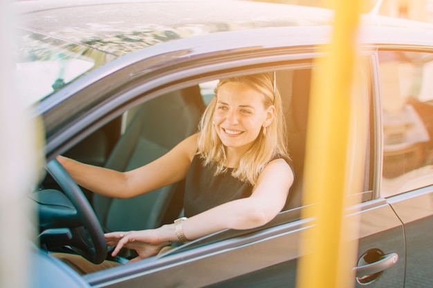 Nahaufnahme der schönen lächelnden jungen Frau, die das Auto fährt